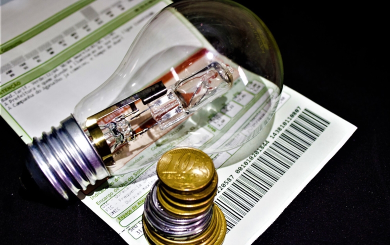 Conta de luz, moedas e lâmpada