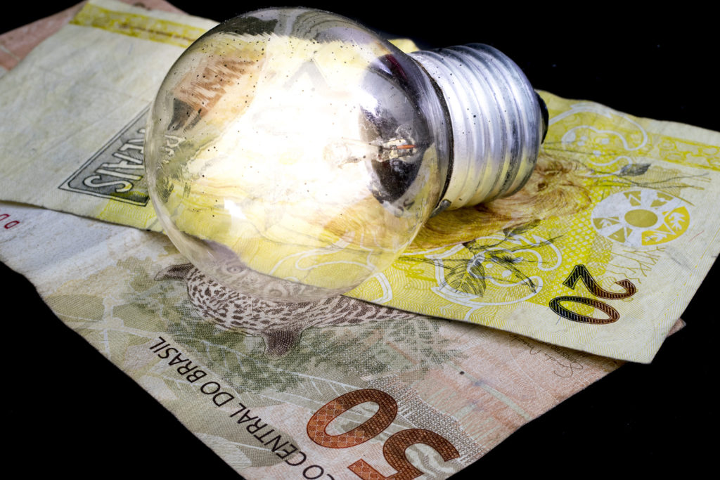 Two Brazilian Real money bank notes and a lit light bulb on top, money idea and concept